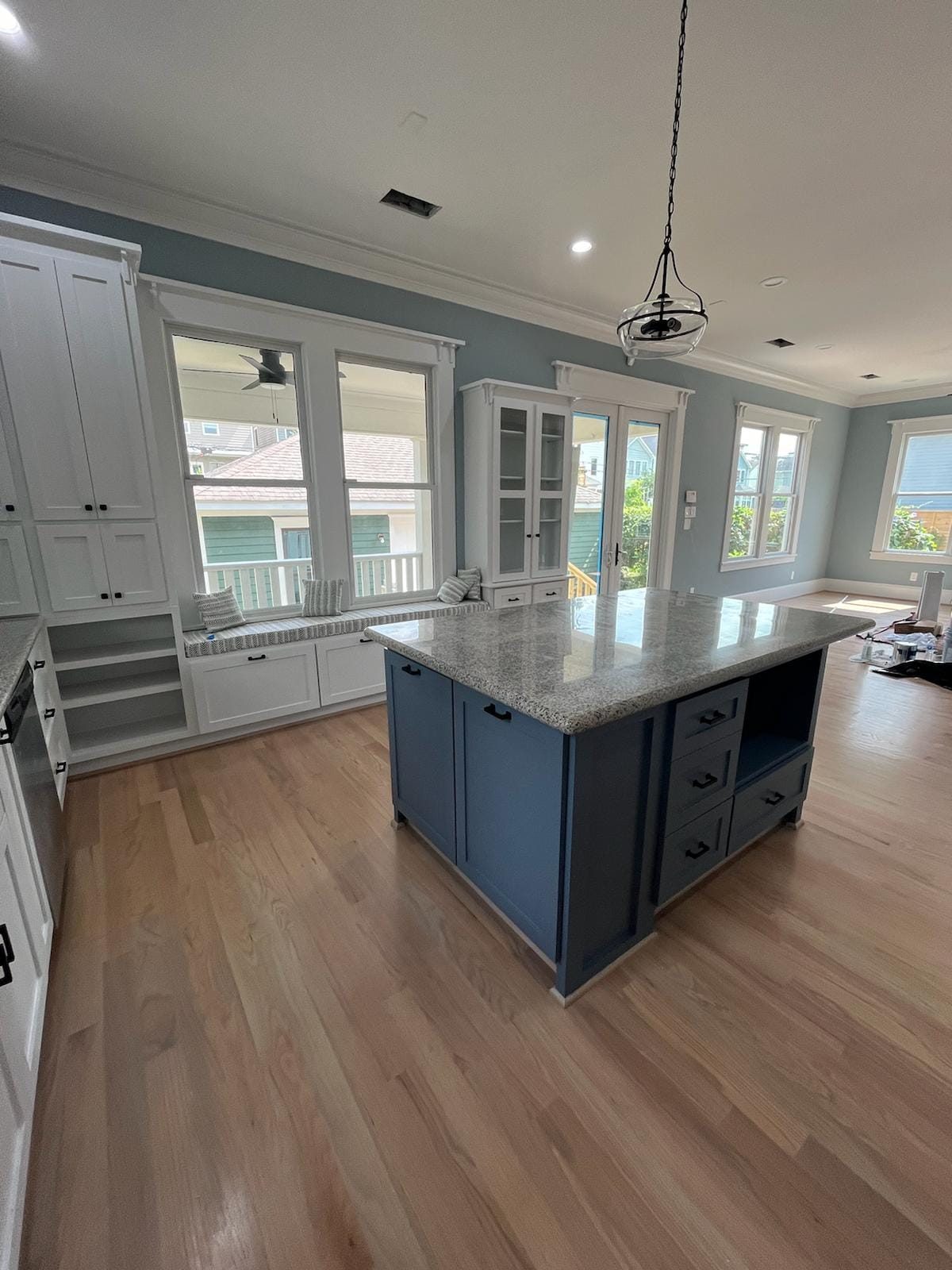 Blue kitchen island and window-seat cabinetry remodel with open living space beyond