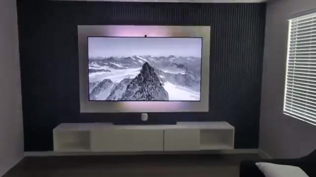 TV on a dark wood-slat media wall with LED backlight above a white floating console