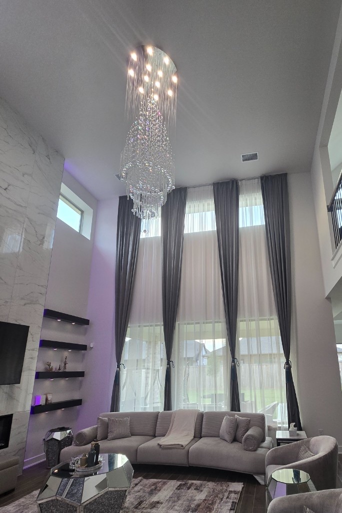 Floor-to-ceiling charcoal drapes and sheer panels on tall living-room windows