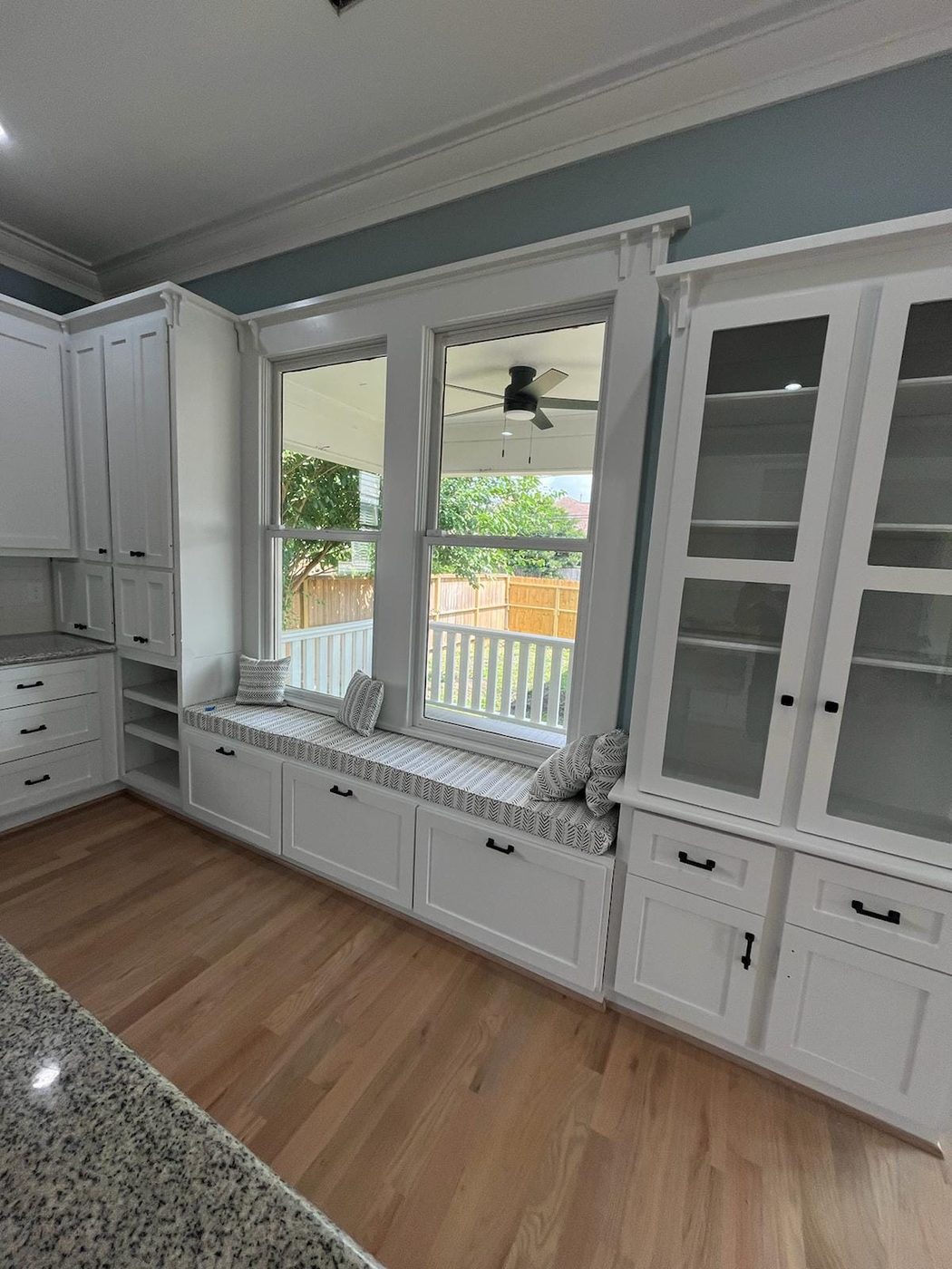 Custom white window-seat built-in hutch with open shelving and drawer storage