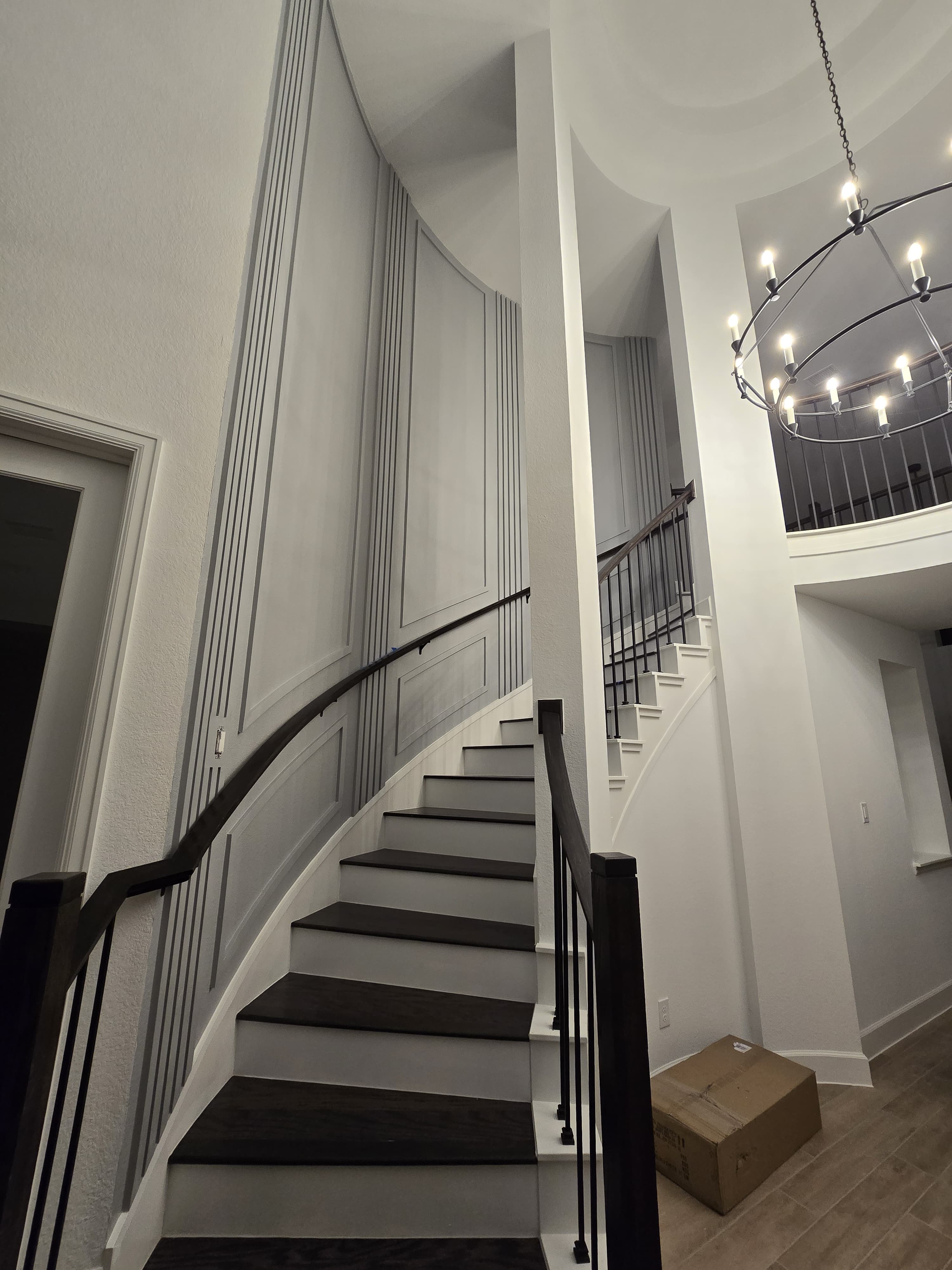 Curved staircase with light-gray fluted wall paneling and dark wood handrail.