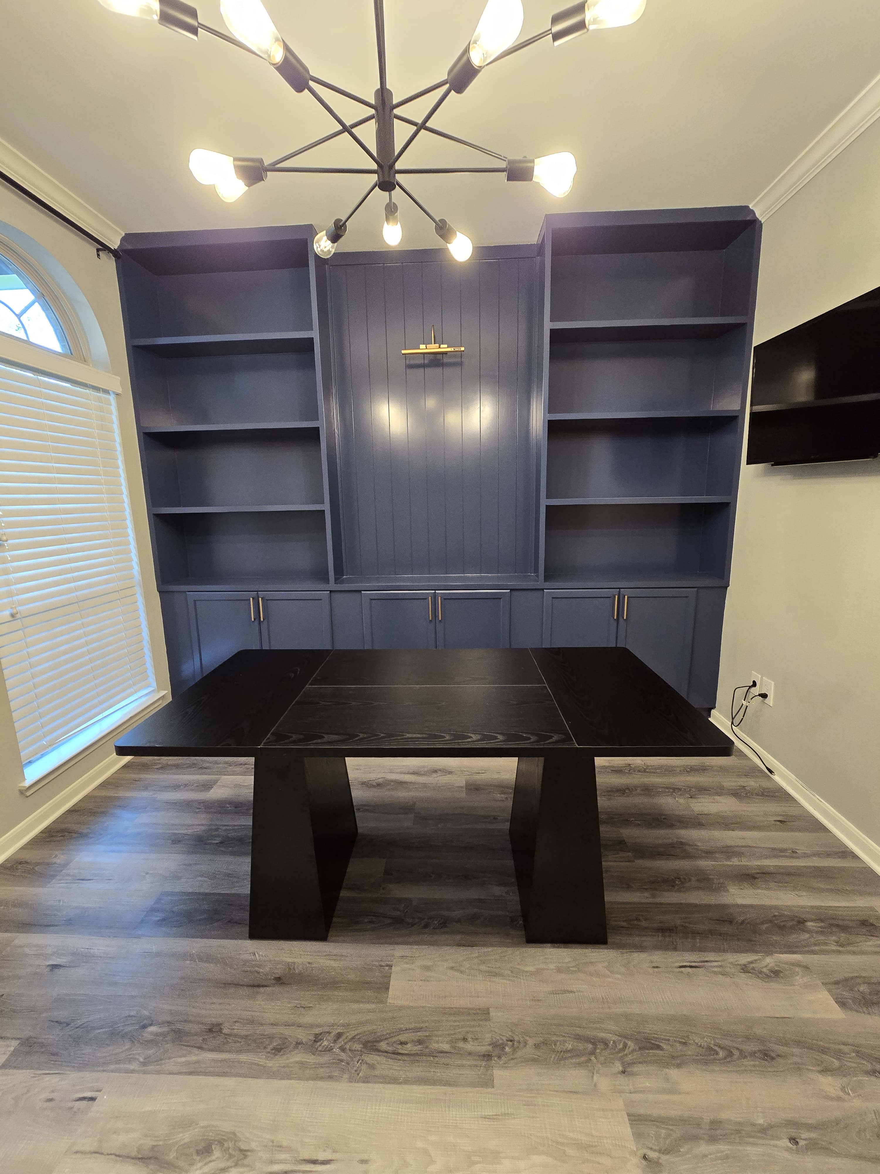 Floor-to-ceiling navy custom built-in shelving and cabinets in a home office.
