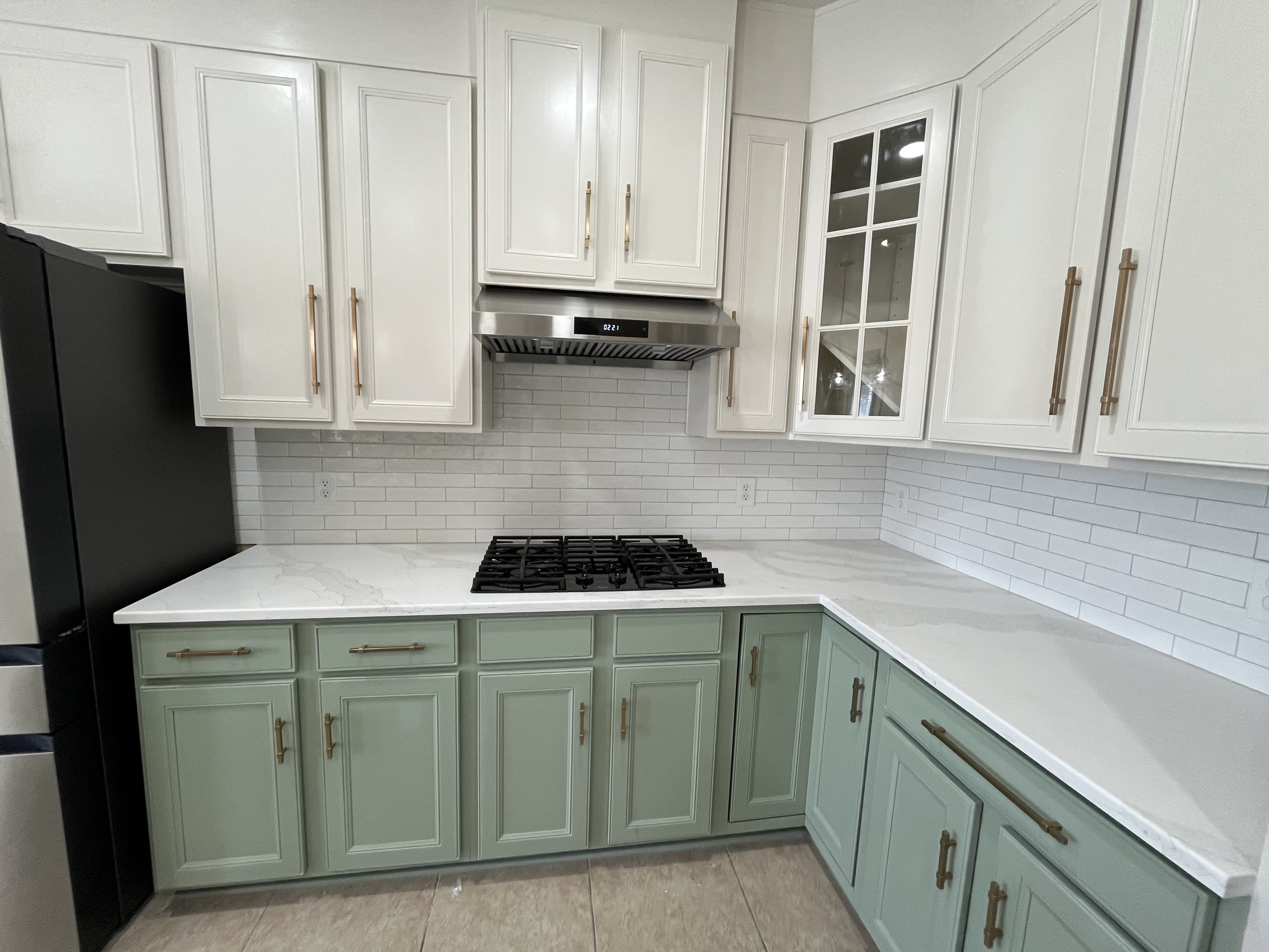 Kitchen corner with white upper cabinets, sage lower cabinets, quartz, and subway tile.