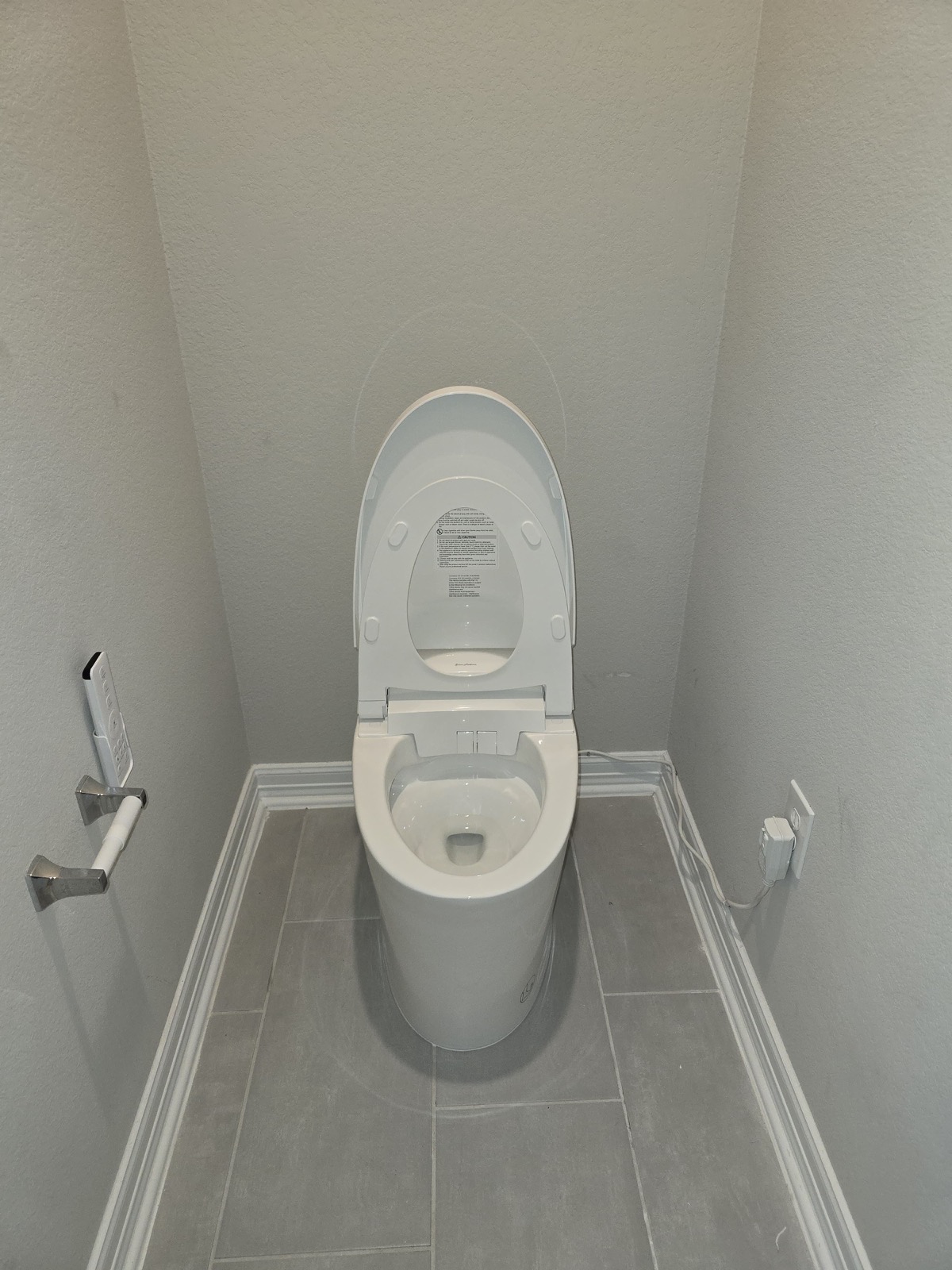 Modern skirted toilet and bidet-seat installation in a gray-tiled bathroom alcove
