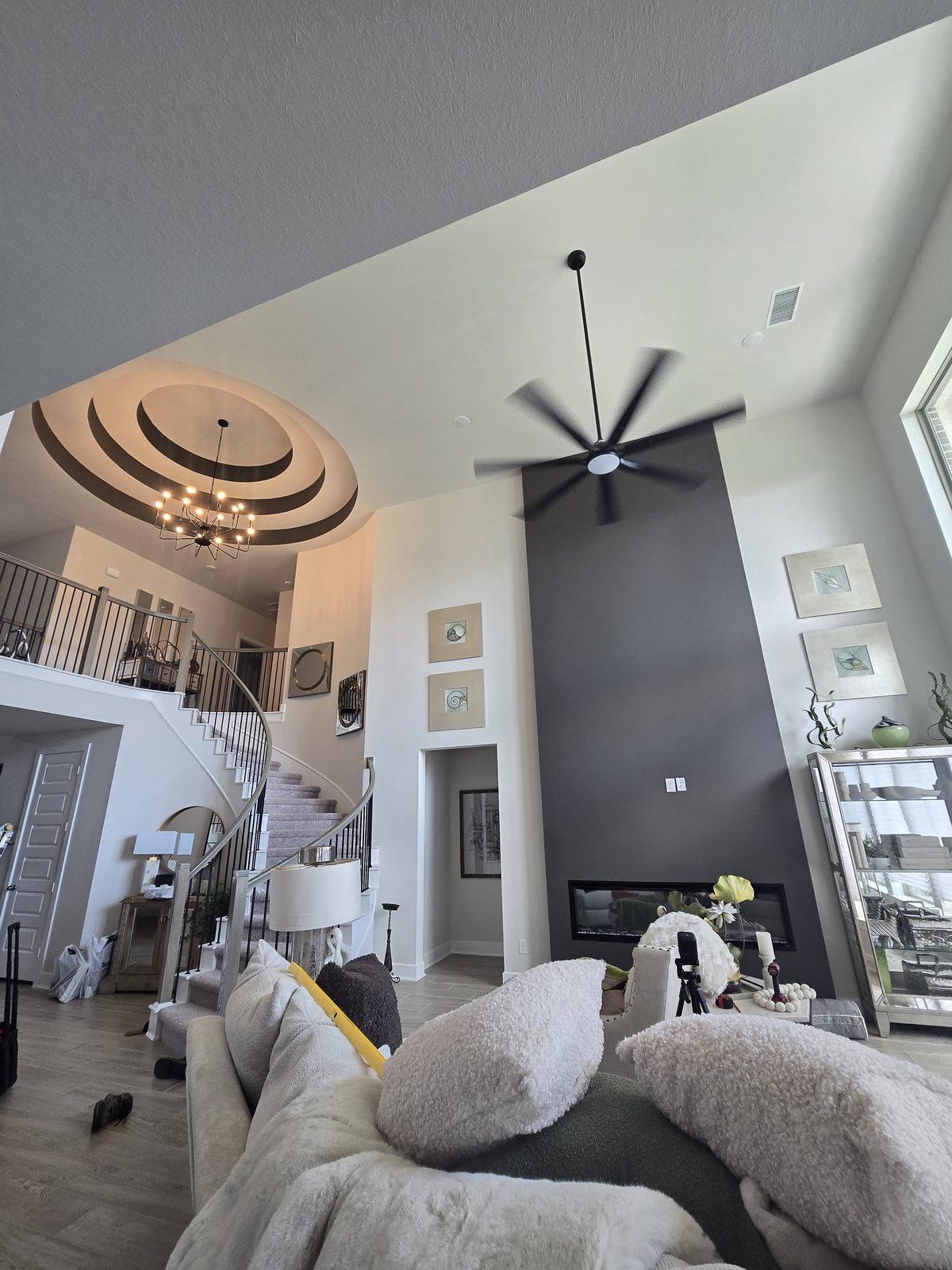 Ceiling fan and chandelier installed on a high vaulted living-room ceiling