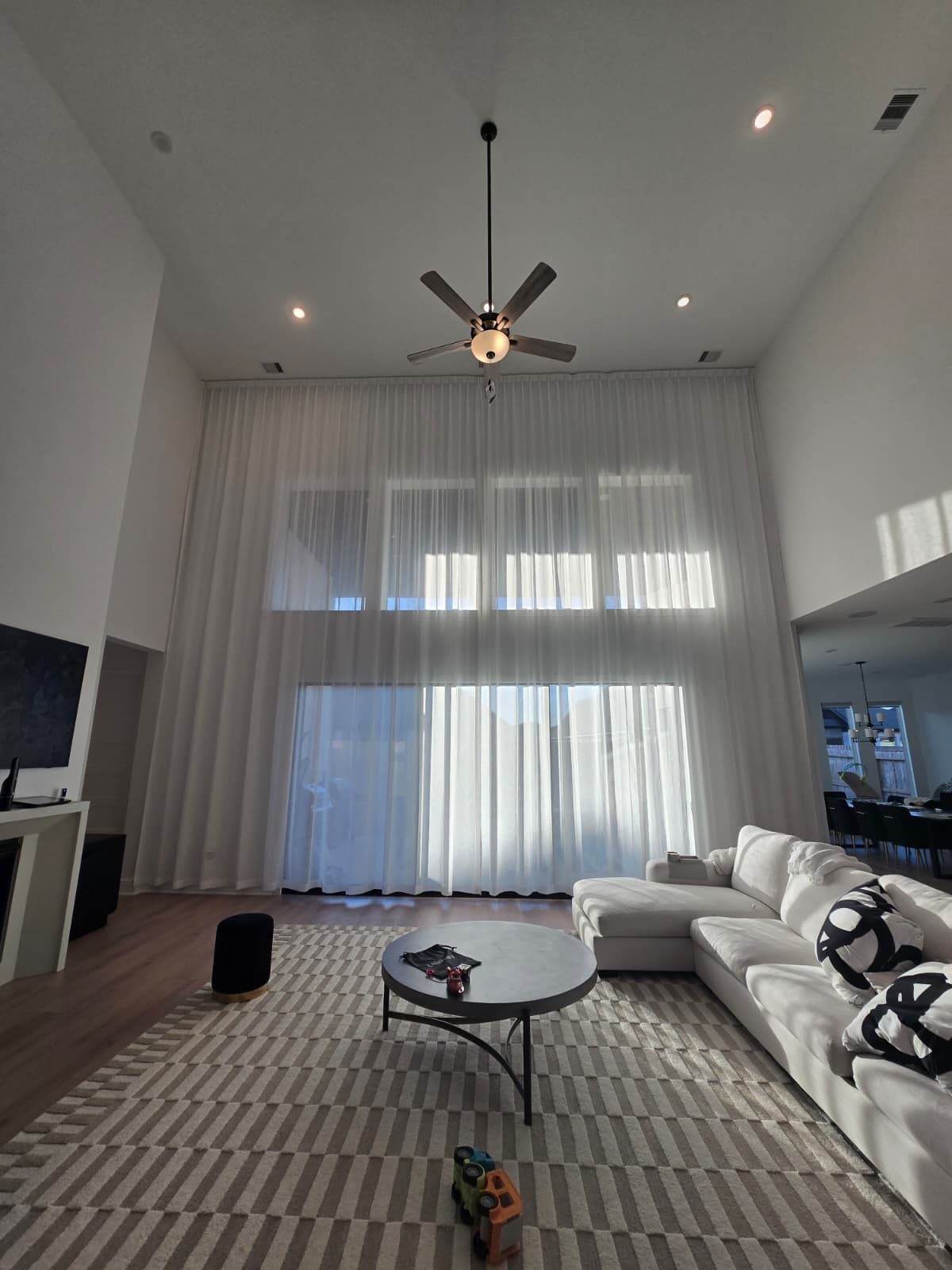 Double-height sheer curtain panels hung on tall living-room windows