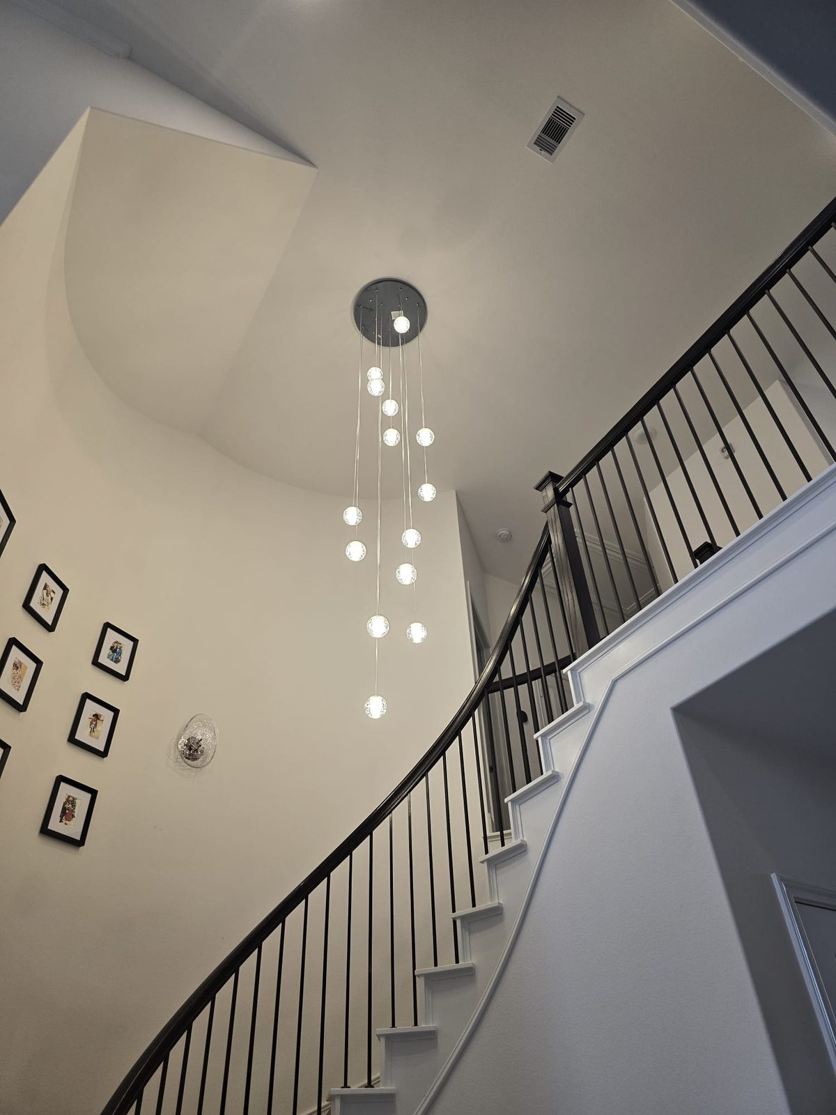 Multi-pendant globe chandelier installed in a two-story foyer
