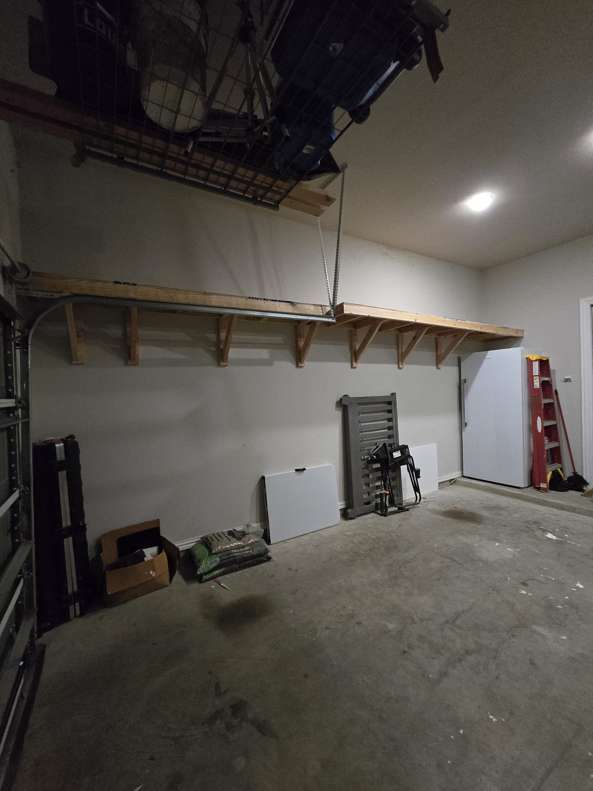 Overhead garage storage rack with wood framing and bike hoist installed above a garage wall