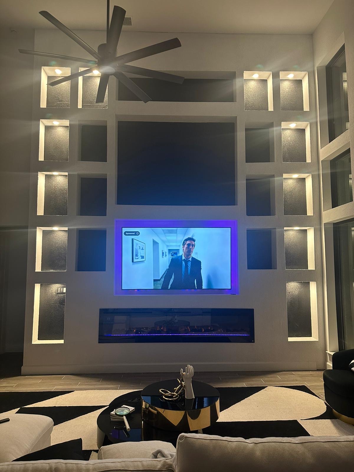 Custom floor-to-ceiling media wall with recessed TV, linear fireplace, and lit niches