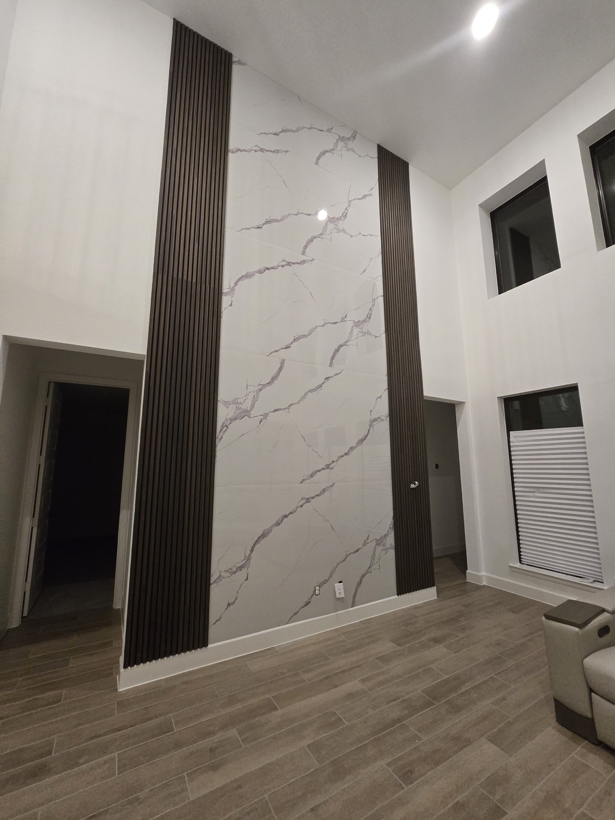 Floor-to-ceiling marble-look tile feature wall flanked by dark vertical wood slats