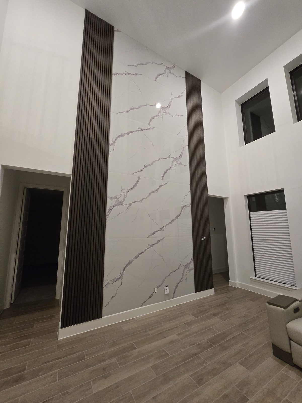 Living-room feature wall with marble-look tile and dark vertical wood-slat accents